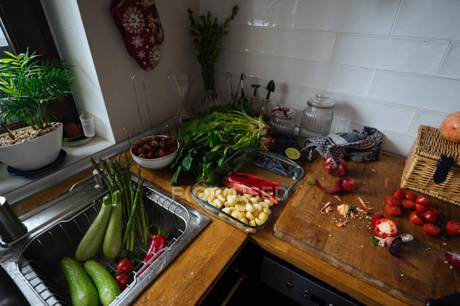 Fresh vegetables on kitchen tabletop and in sink — Stock Photo