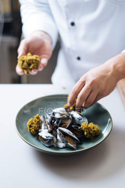 Close-up de chef em uniforme branco servindo prato de frutos do mar nórdicos com mexilhões no prato — Fotografia de Stock