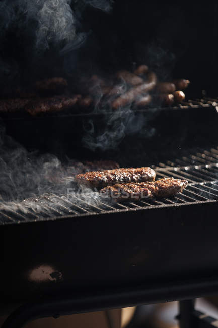Сирі бургерні пиріжки обсмажуються на сітці гриля барбекю на відкритому повітрі — стокове фото