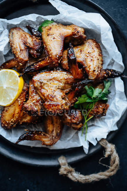 Close-up de assadeira de asas de frango assadas em gergelim e salsa com limão — Fotografia de Stock