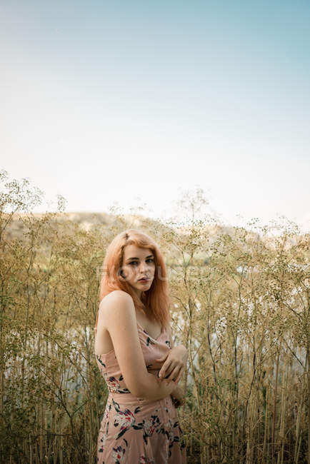 Young blonde woman posing in tall grass on lake shore — Stock Photo
