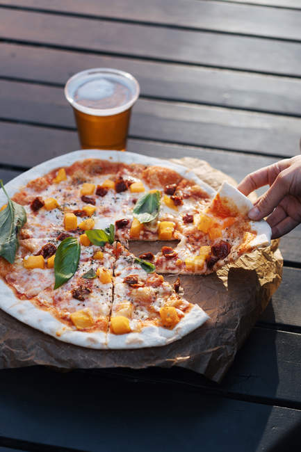Nahaufnahme einer weiblichen Hand, die ein Stück Pizza nimmt — Stockfoto