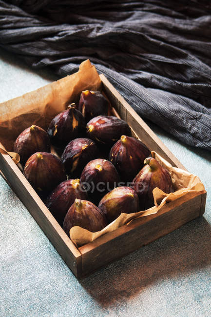 Figues fraîches sur parchemin dans une boîte en bois — Photo de stock