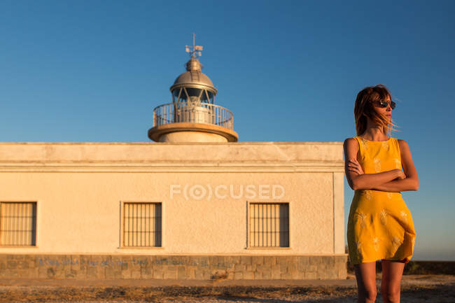 Woman in dress standing on shoreline in front of lighthouse — Stock Photo