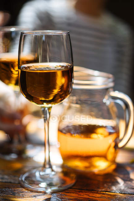 Крупный план бокалов белого вина и кувшина на деревянном столе — стоковое фото