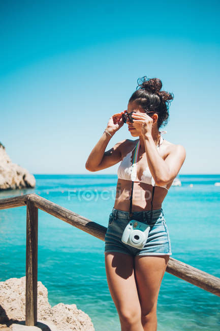 Young girl in summer clothes leaning on wooden handrail on beach — Stock Photo