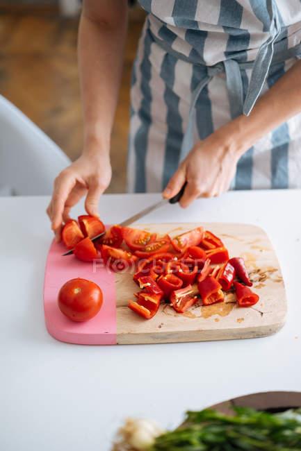 Жінка тримає різання червоний перець і помідори на Розробні рада — стокове фото