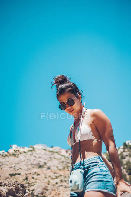 Giovane ragazza con macchina fotografica a piedi sulla costa rocciosa — Foto stock