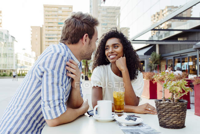 Pareja multirracial romántico sentado en la cafetería al aire libre juntos - foto de stock