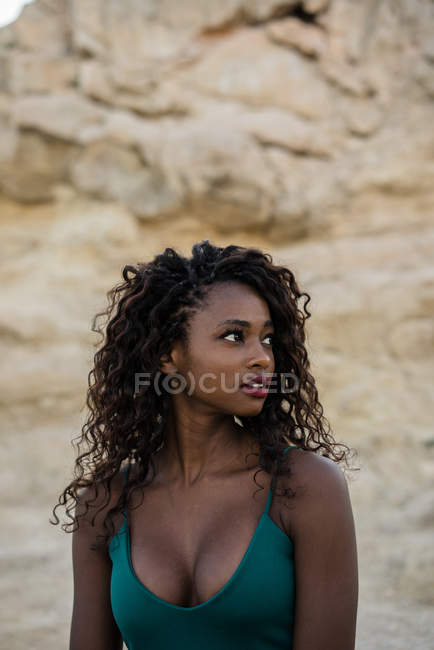 Retrato de mulher bonita com cachos em pé contra rochas — Fotografia de Stock