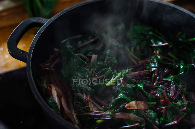 Cooking spinach leaves in pot on gas stove — Stock Photo