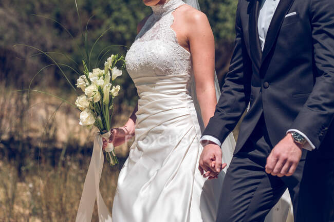 Супруги в свадебной одежде держатся за руки — стоковое фото