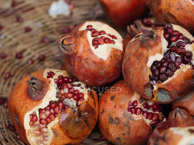 Partly peeled organic pomegranates in wicker basket — Stock Photo