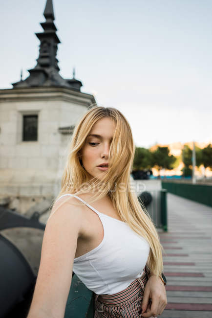 Sensual young woman in white tank top standing on city street — Stock Photo