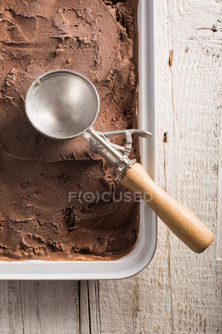 Hausgemachtes Schokoladeneis in Schachtel mit Schaufel auf Holzoberfläche — Stockfoto