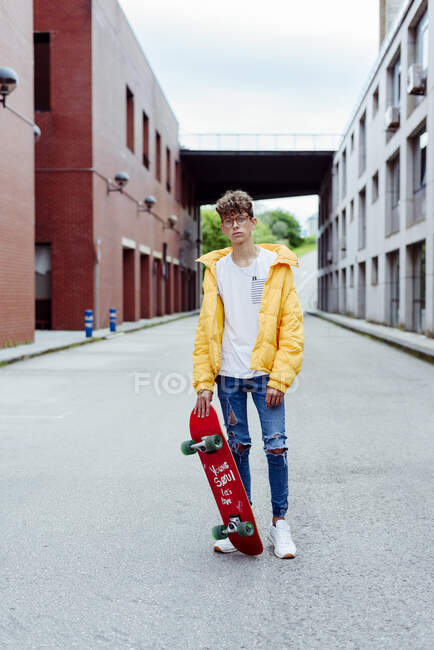 Підліток зі скейтбордом, що стоїть на вулиці — стокове фото