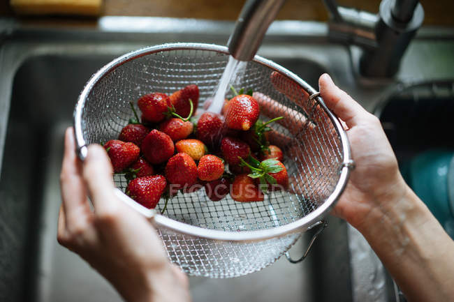 Mains humaines laver les fraises sous robinet d'évier — Photo de stock