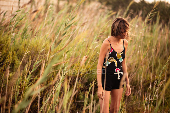 Junge Frau im Sommeroutfit steht im hohen Gras auf Feld — Stockfoto