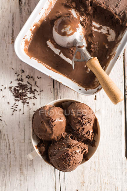 Homemade chocolate ice cream in bowl and in box on wooden surface — Stock Photo