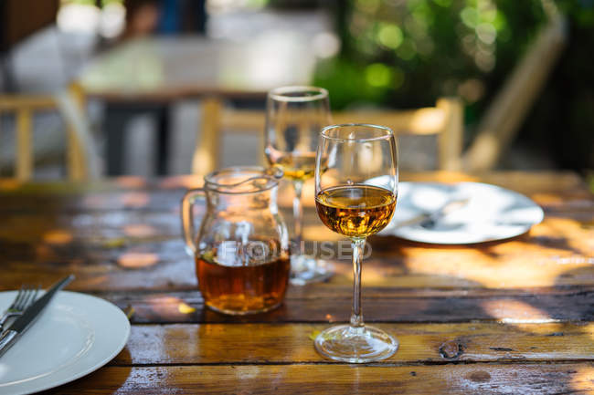 Крупный план бокалов белого вина и кувшина на деревянном столе — стоковое фото
