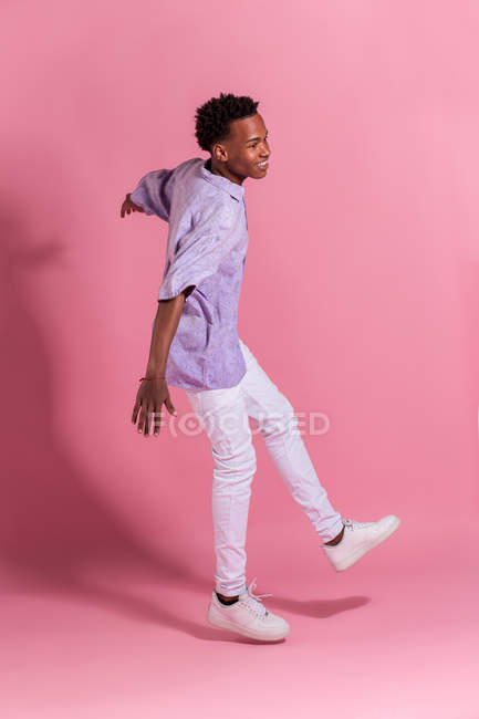 Стильний веселий молодий чоловік танцює на рожевому фоні — стокове фото