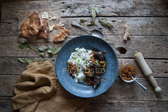 Roasted eggplants and rice with spices in plate on rustic wooden table — Stock Photo