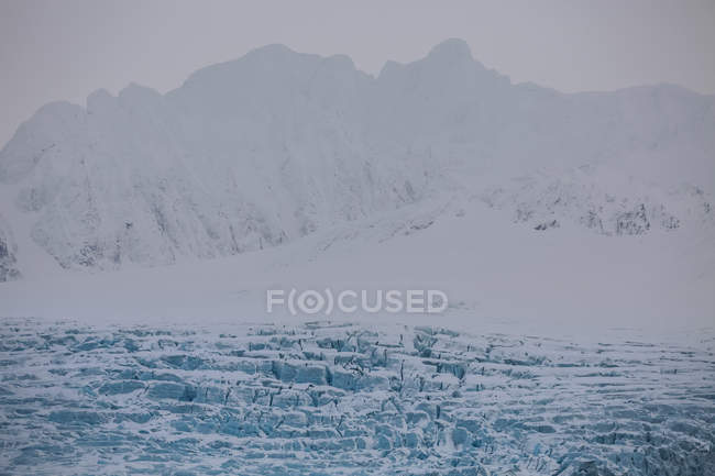 Лед, плавающий в воде с силуэтом гор на заднем плане, Шпицберген, Норвегия — стоковое фото