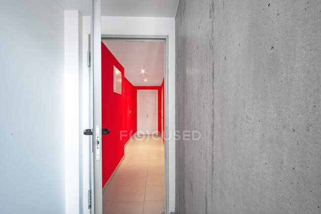 Интерьер красного офисного коридора через открытую дверь в современном здании — стоковое фото