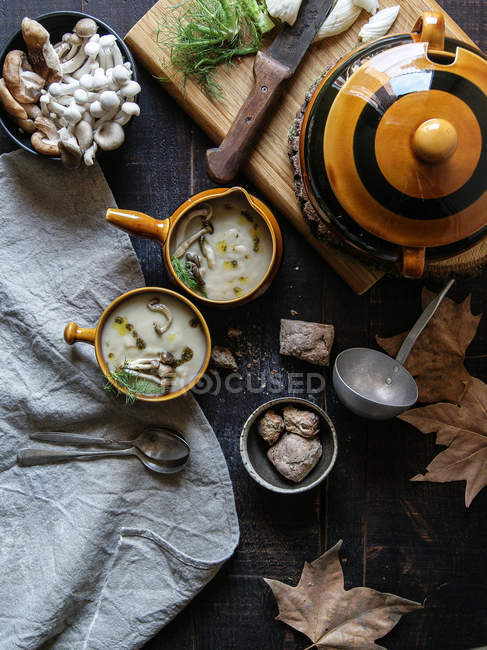 Servido en cuencos sabrosa crema de champiñones en mesa de madera rústica con ingredientes - foto de stock