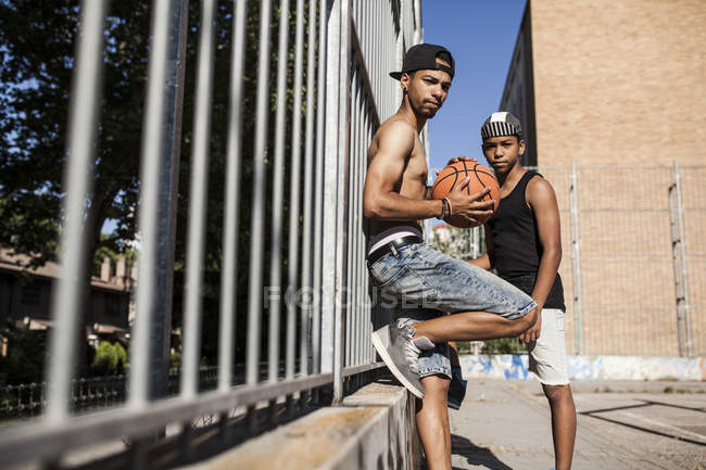 Afro jeunes frères debout avec le basket-ball dans le court à l'extérieur — Photo de stock