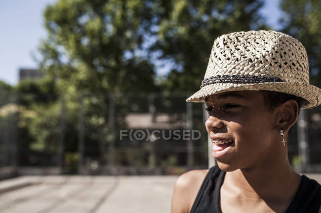 Sonriente niño en sombrero de paja de pie al aire libre y mirando hacia otro lado - foto de stock