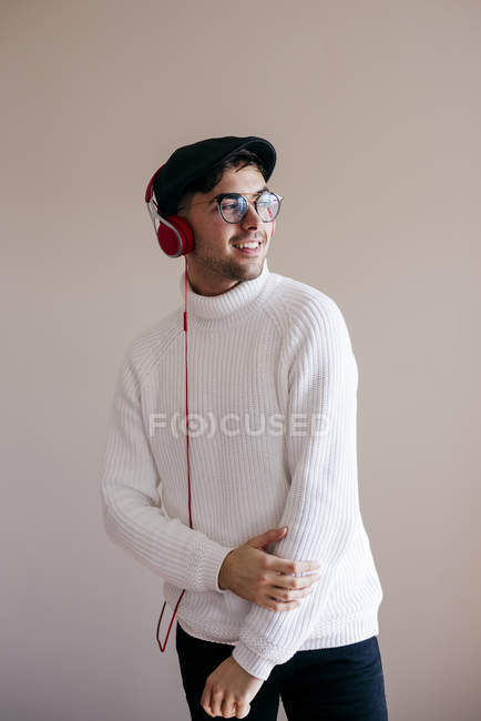 Випадковий чоловік з навушниками, що стоять на сірому фоні — стокове фото