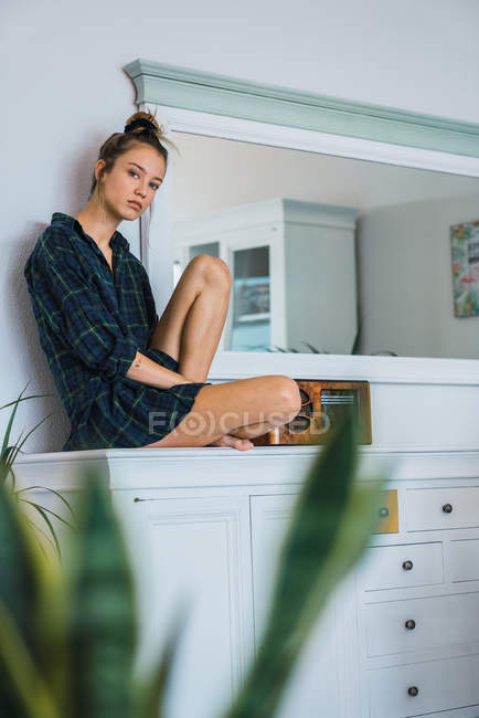 Lovely woman in checkered oversize shirt sitting near radio unit — Stock Photo