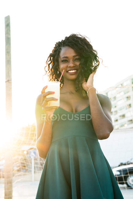 Retrato de mulher negra com bebida em pé na frente da rede em backlit — Fotografia de Stock