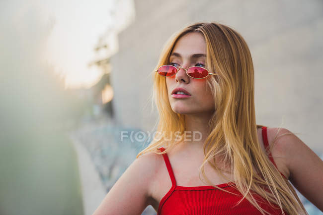 Молода жінка у верхній частині танка та сонцезахисні окуляри, що стоять на відкритому повітрі — стокове фото