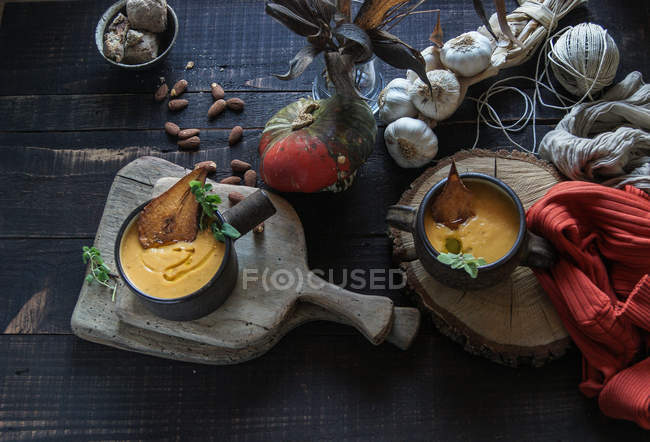 Pumpkin cream soup served with dried pears on rustic wooden table with ingredients — Stock Photo