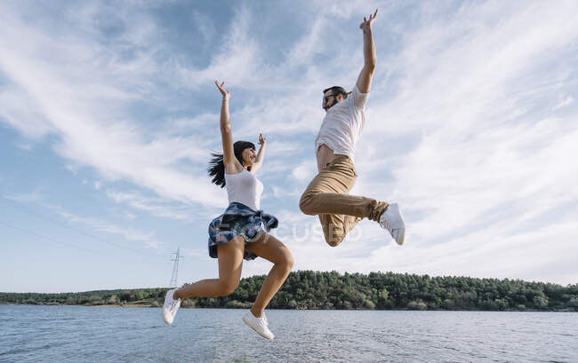 Mann und Frau springen an den See. — Stockfoto