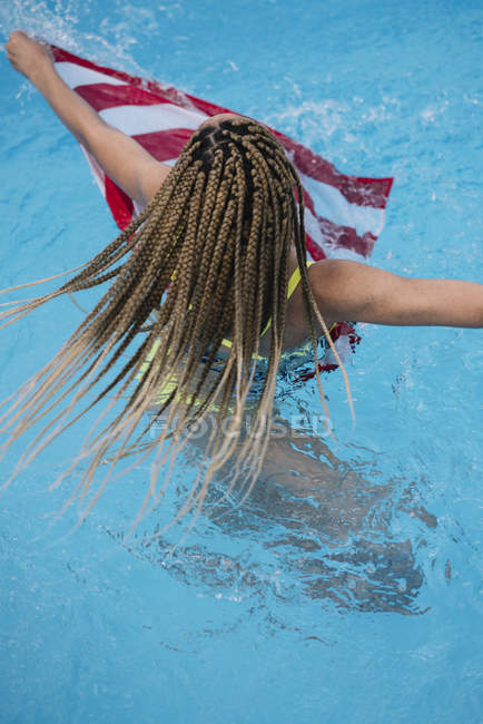Vista posteriore della donna in piscina con bandiera americana — Foto stock