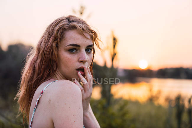 Portrait de la jeune femme aux taches de rousseur séduisante debout dans la nature au coucher du soleil — Photo de stock