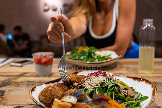 Close-up da mão feminina com garfo atingindo comida de tigela no café — Fotografia de Stock