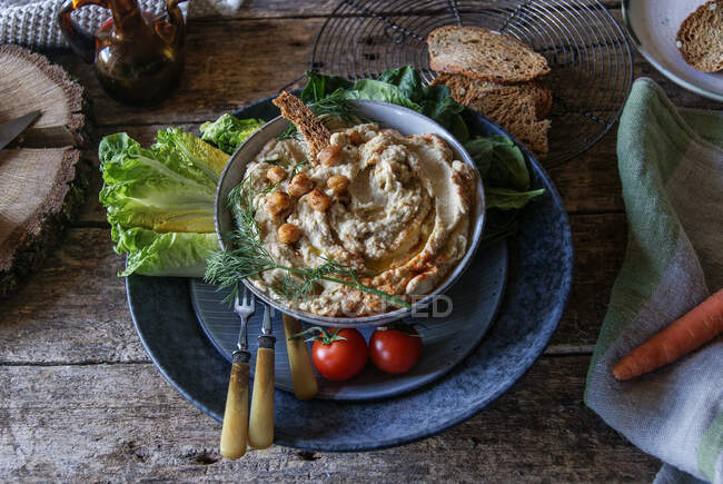 Piatto con delizioso hummus di carciofo con pane su sfondo scuro — Foto stock