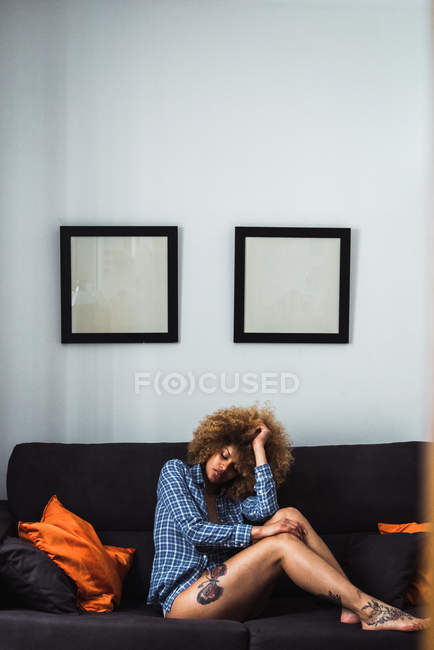 Mujer atractiva sentada en el sofá en casa - foto de stock
