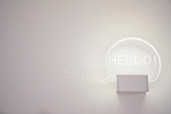 Lâmpada brilhante com boa inscrição Olá pendurado na parede branca — Fotografia de Stock