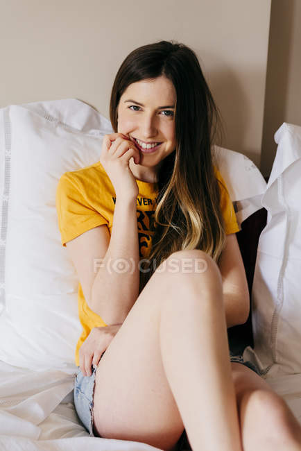 Mulher muito sorridente deitada na cama e olhando para a câmera — Fotografia de Stock