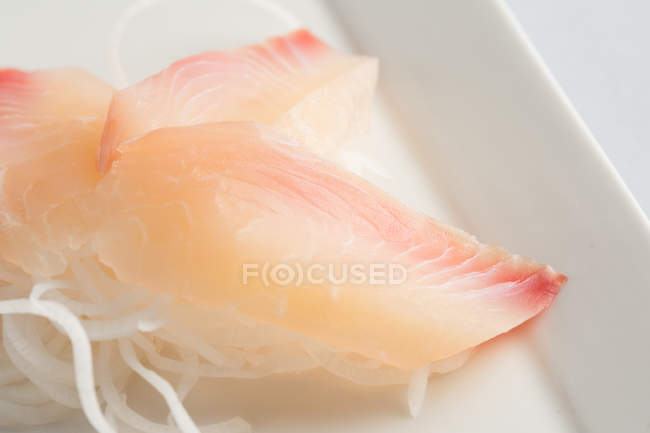 Sashimi tradicional japonés con daikon sobre fondo blanco - foto de stock