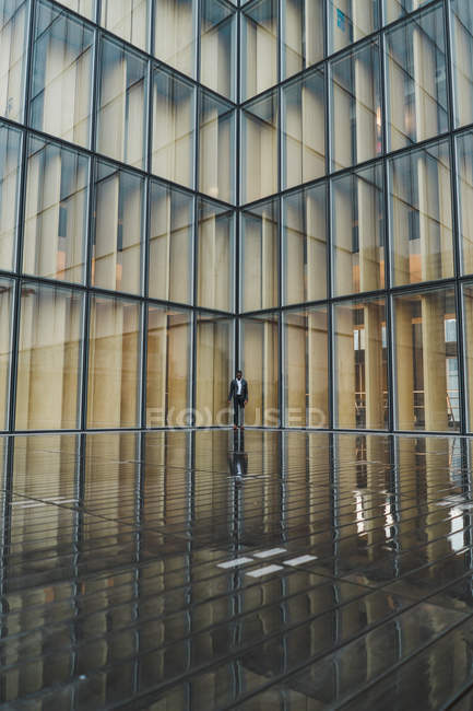 Homme d'affaires marchant sur la chaussée contre le bâtiment en verre moderne — Photo de stock