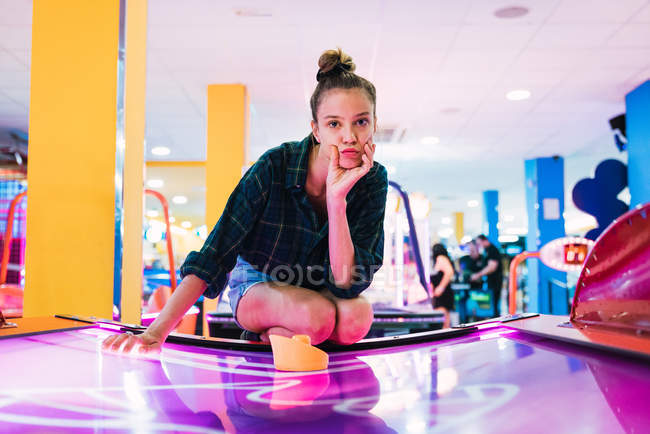 Junge Frau liegt auf Airhockeytisch und blickt in Kamera — Stockfoto