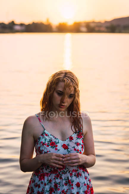 Sinnliche Frau in Kleid steht im Wasser des Sees bei Sonnenuntergang — Stockfoto