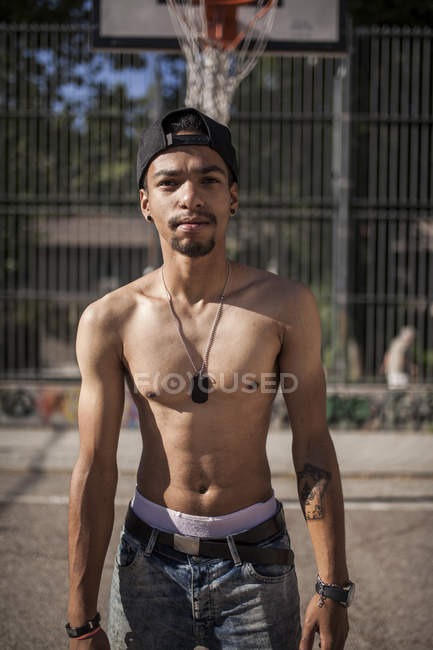 Sin camisa joven afro chico de pie en baloncesto cancha al aire libre - foto de stock