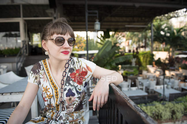 Elegante junge Frau sitzt auf der Terrasse und schaut weg — Stockfoto